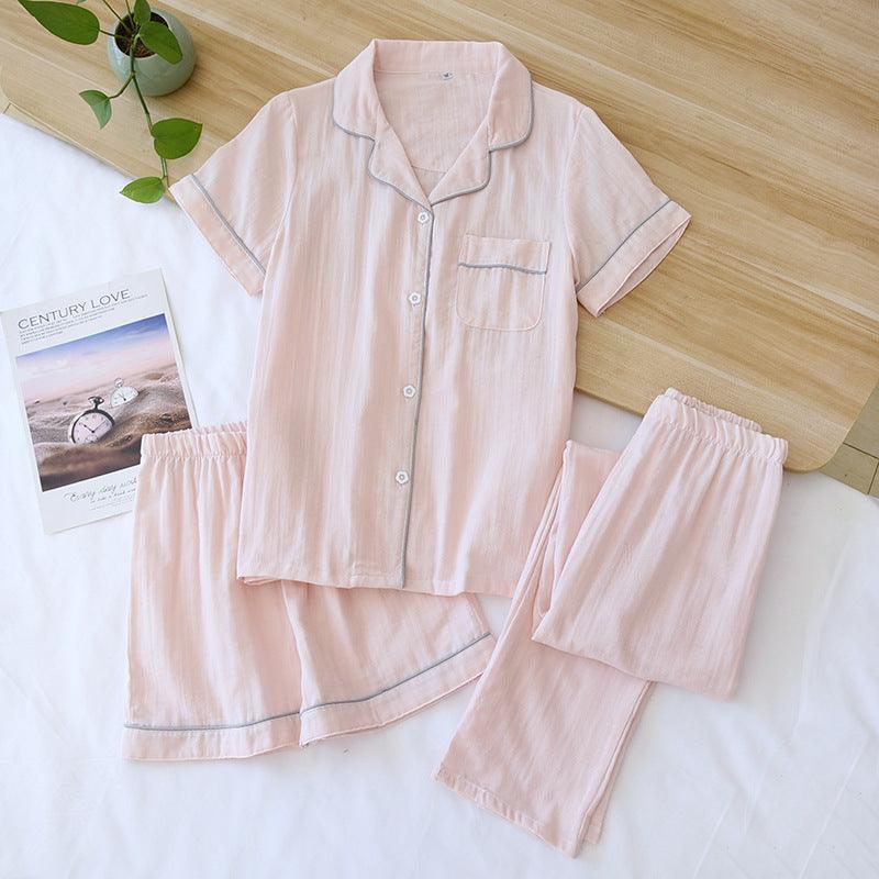 Three-piece cotton gauze pajamas for women in light pink with short sleeves, shorts, and trousers set laid flat on white surface.