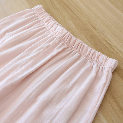 Soft light pink cotton gauze pajama shorts with elastic waistband on wooden surface