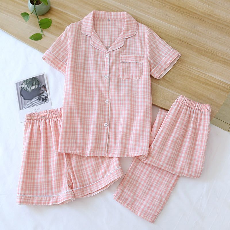 Three-piece cotton gauze pajamas for women in light pink check pattern with short sleeves, shorts, and trousers laid out on a white surface.